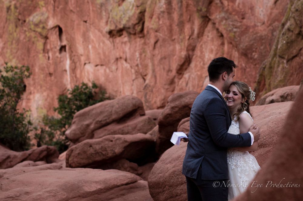 Newlyweds share their first kiss against red rock formations at sunset.