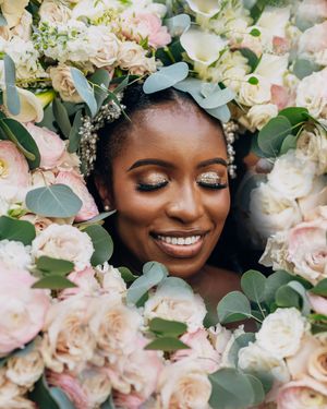 Soft pink and white roses with eucalyptus frame a joyful wedding portrait.