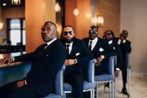 Wedding party dressed in formal black suits sitting in an elegant venue.
