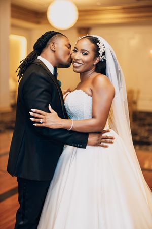 A romantic wedding moment captured in warm lighting showing an intimate embrace between the newlyweds.