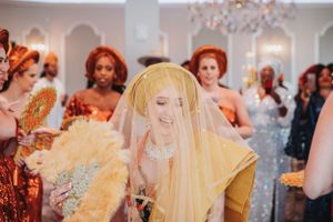 Wedding party celebrating with confetti and smiles in an elegant indoor venue with chandelier lighting.
