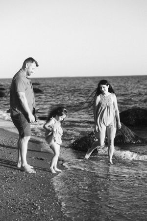 A family enjoys a playful moment together at the water's edge on a beach.
