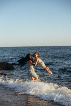 A joyful couple embraces while playing in the ocean waves at the beach.