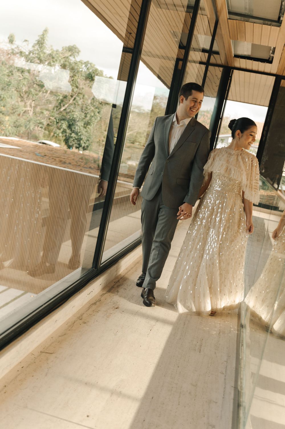 Series of candid wedding photos showing a couple walking together in a modern venue with wood paneled walls and windows.