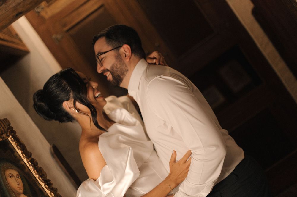 A joyful couple shares an intimate dance, smiling warmly in a warmly lit rustic interior setting.