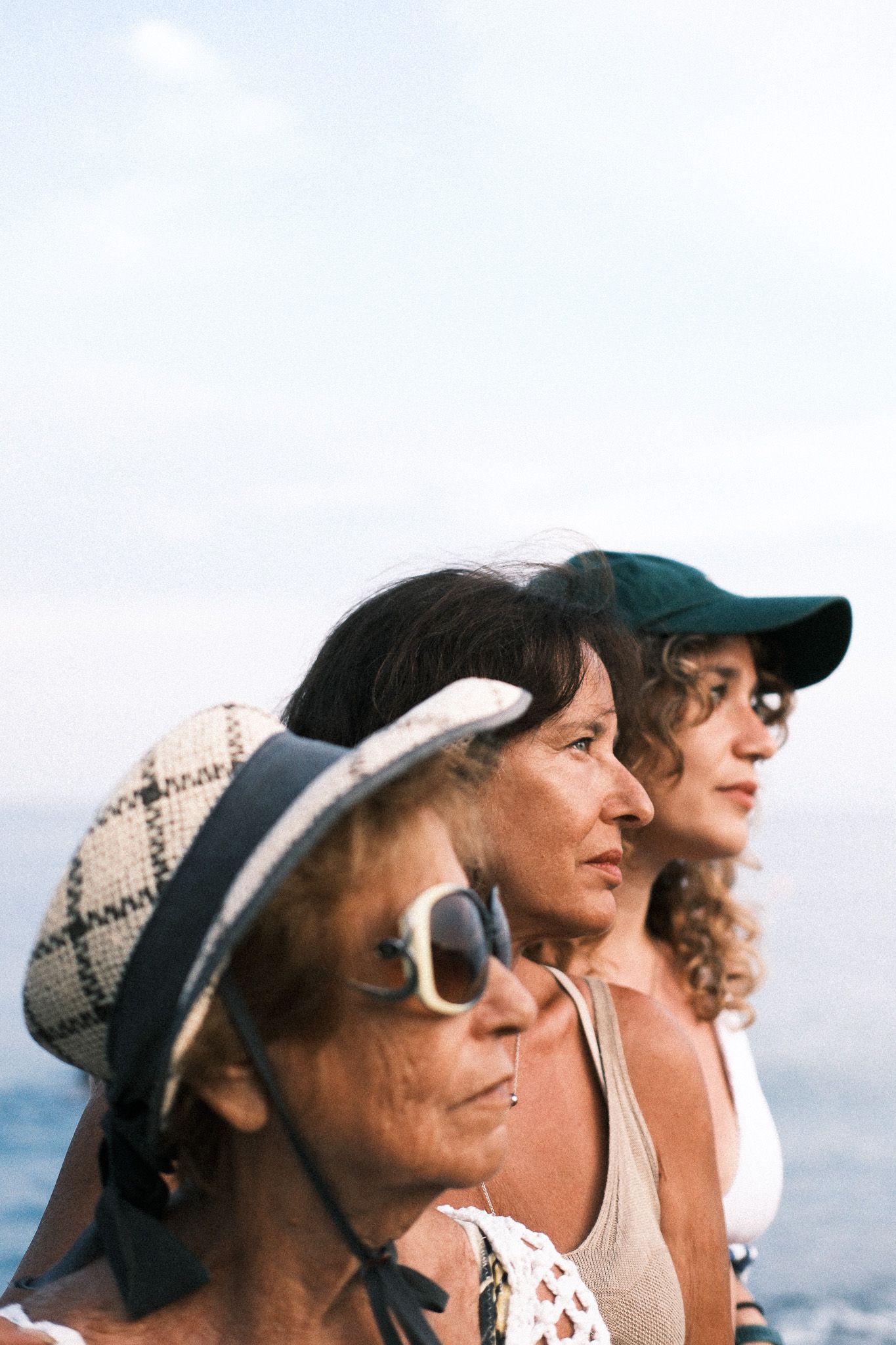 Three generations of women posing together in front of Lake Como for artistic family portrait.