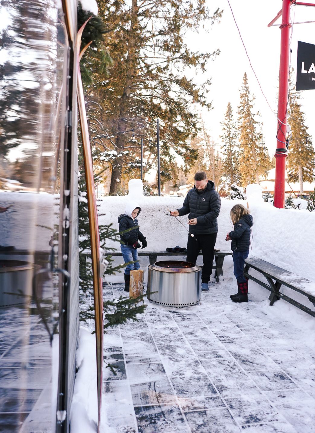 Snowy ski resort scene with people gathered around outdoor equipment.