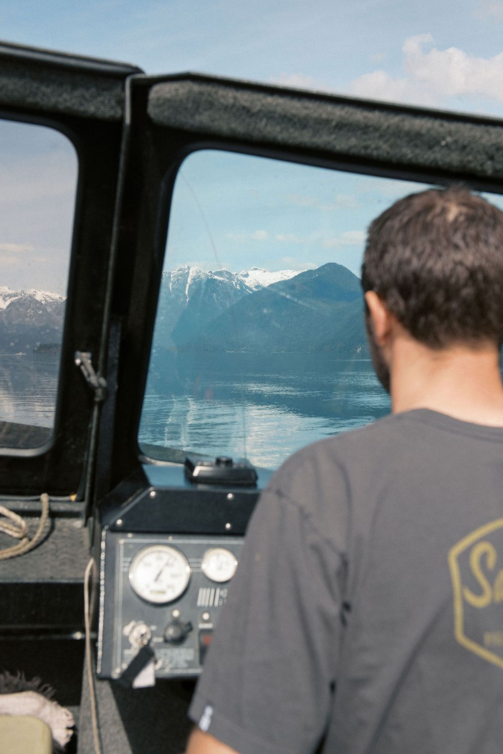 View through boat window showing mountain lake landscape and control panel.