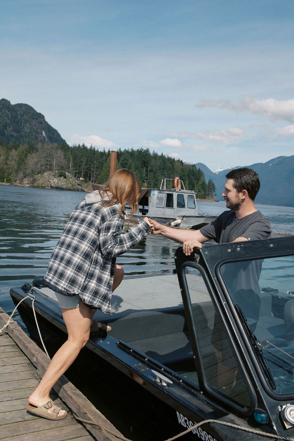 Boating scene at a scenic mountain lake dock with evergreen trees.