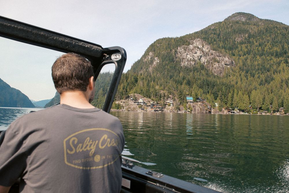 Scenic mountain lake view from boat dashboard showing forested shoreline.