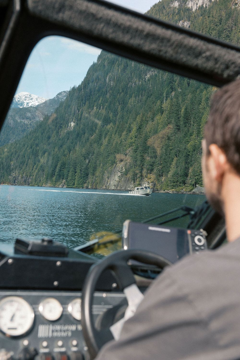 View through boat windshield of mountainous coastline on sunny day.
