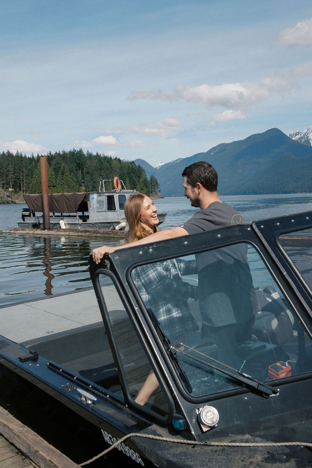 Peaceful mountain lake scene with people in a boat near a wooden dock.