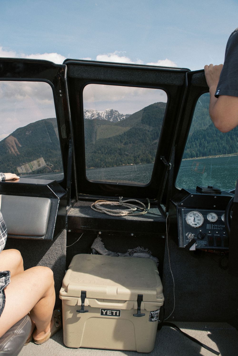 Interior view of boat dashboard with mountains visible through windshield.