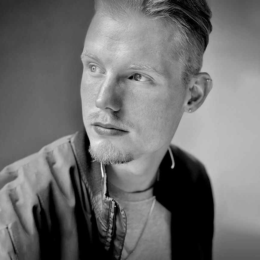 Black and white portrait photograph shows intense side lighting on a contemplative expression wearing a casual jacket.