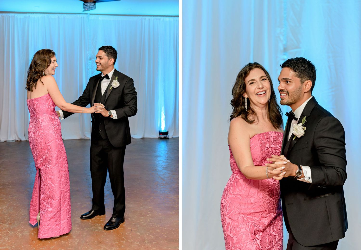 A couple dances lovingly together at a wedding reception in front of a white backdrop illuminated by blue lights.