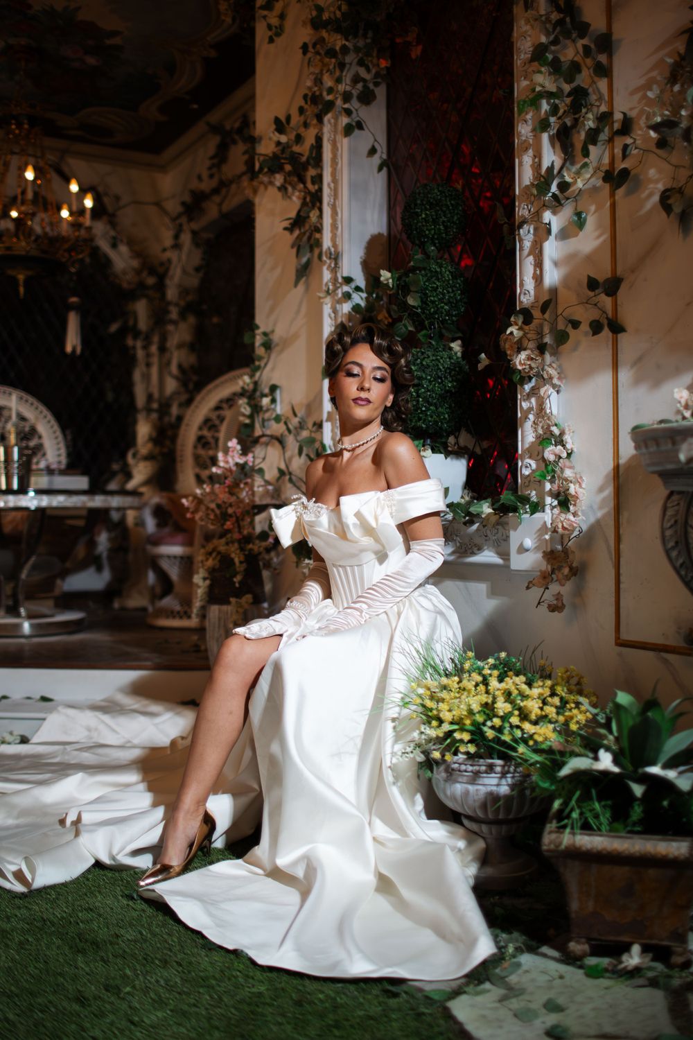 Elegant off-shoulder white wedding gown in a luxurious setting with ivy and chandeliers.