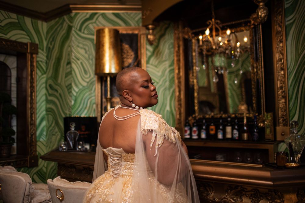 A wedding celebration at an elegant venue with vintage decor, ornate mirrors, chandeliers and green wallpaper.