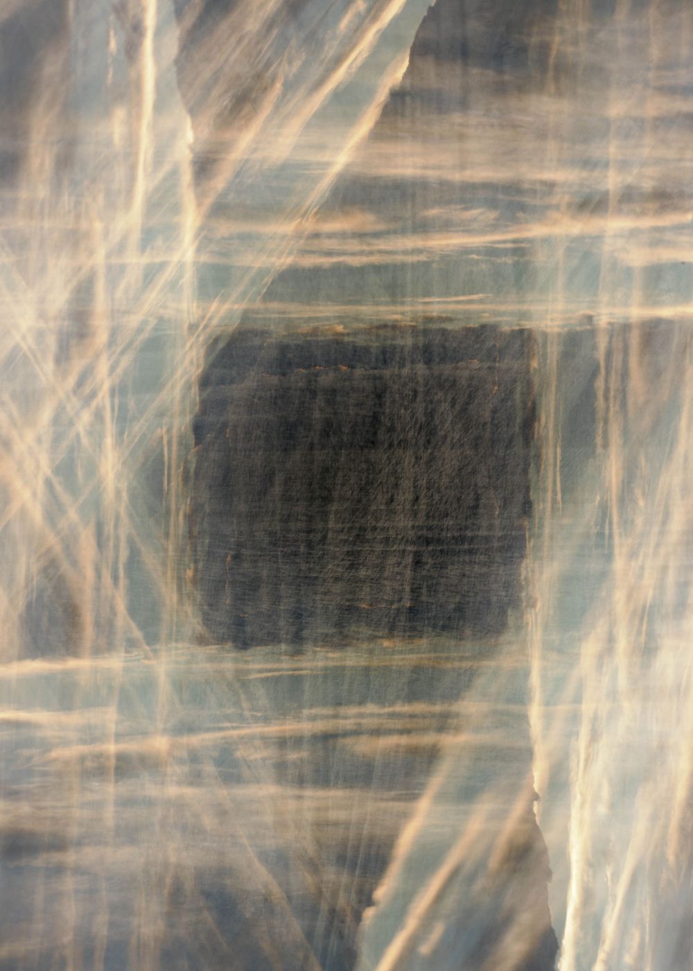 Abstract artistic photograph with dark center and wispy light streaks creating ethereal patterns against a muted background.