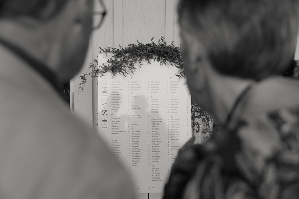 People looking at text posted on a wall captured in black and white photography.