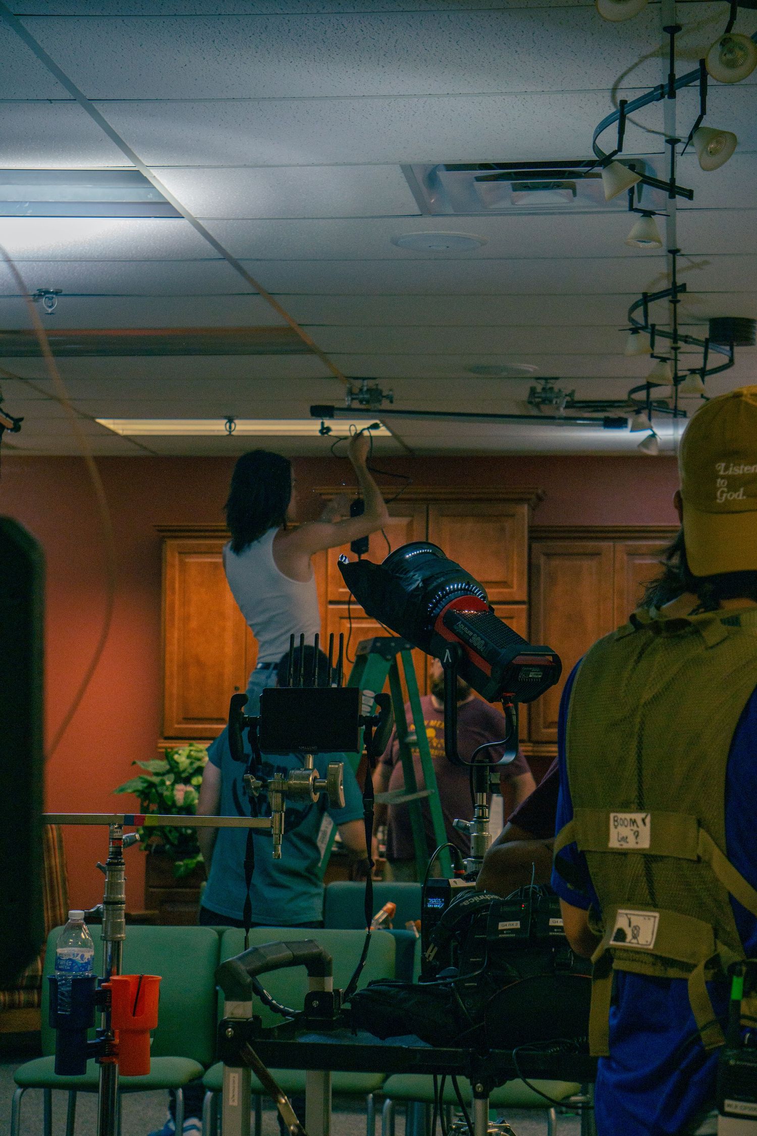 A young man rigging a light on a a ceiling
