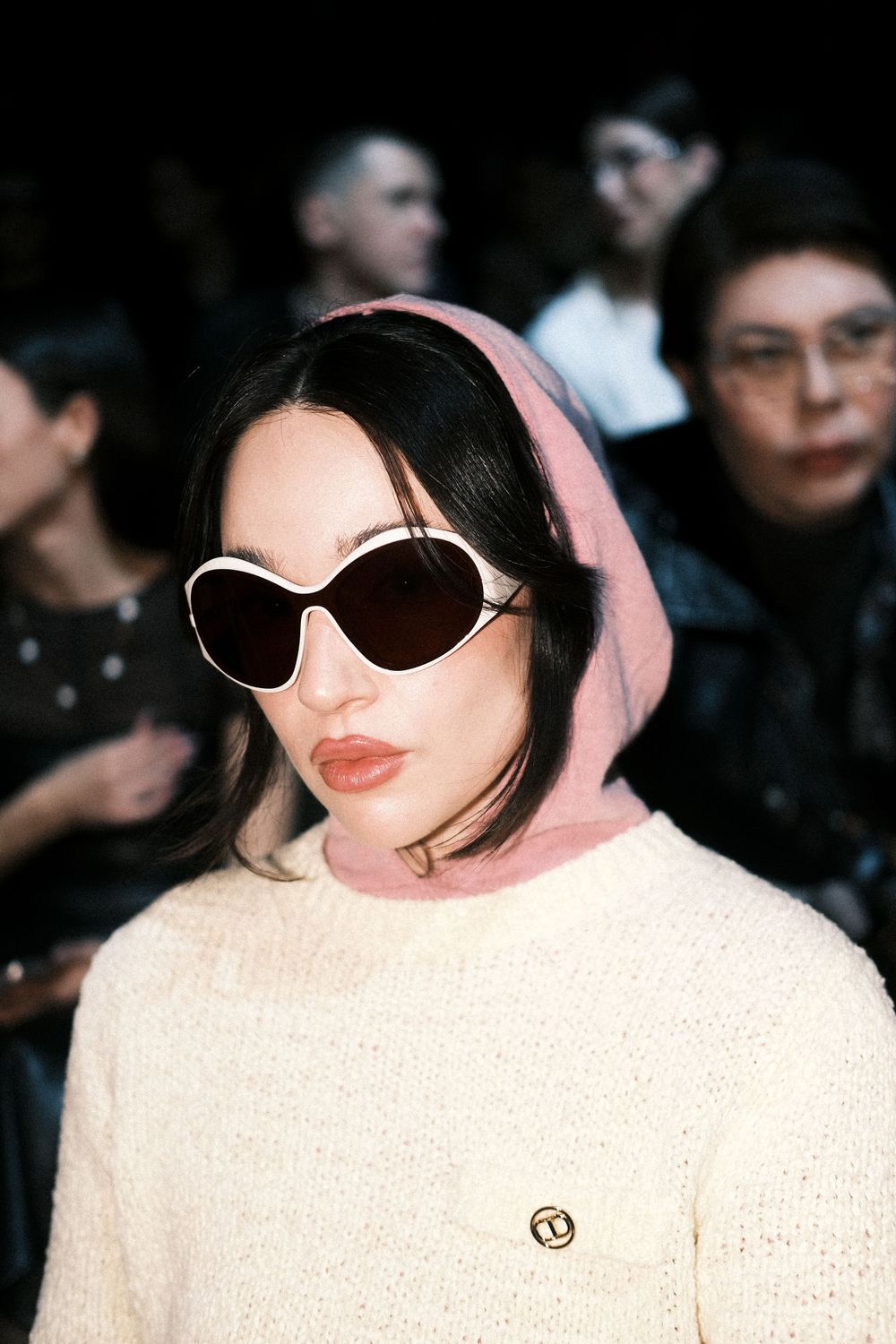 Guest watching intently as a model showcases a structured look on the catwalk at Milan Fashion Week.