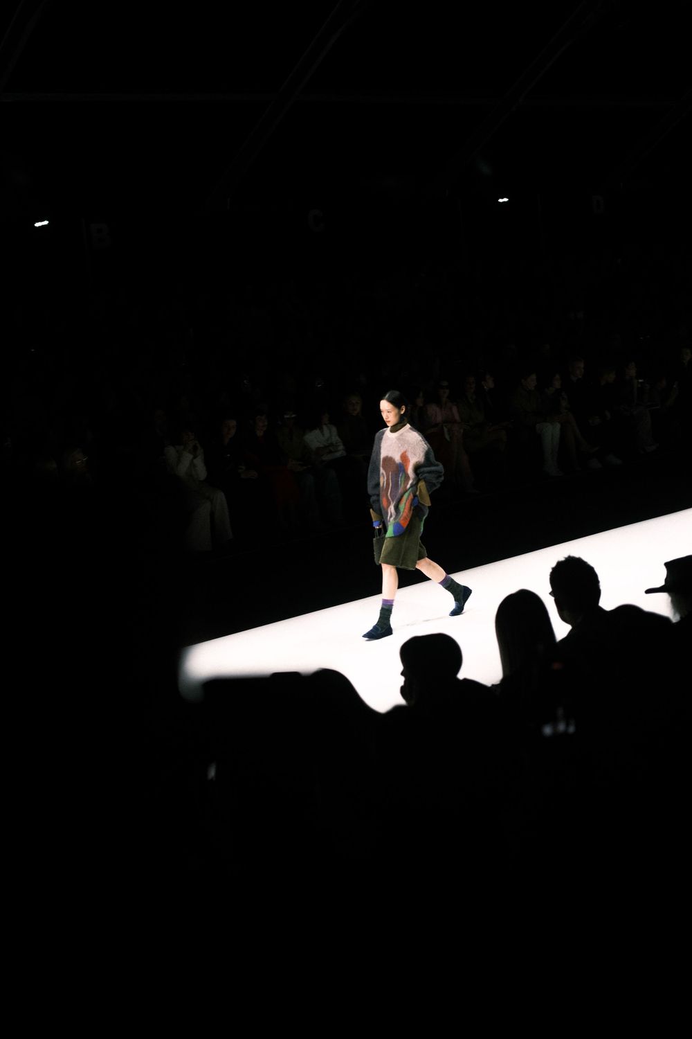 Model walking a minimalist runway in Milan during a luxury fashion house’s private event.