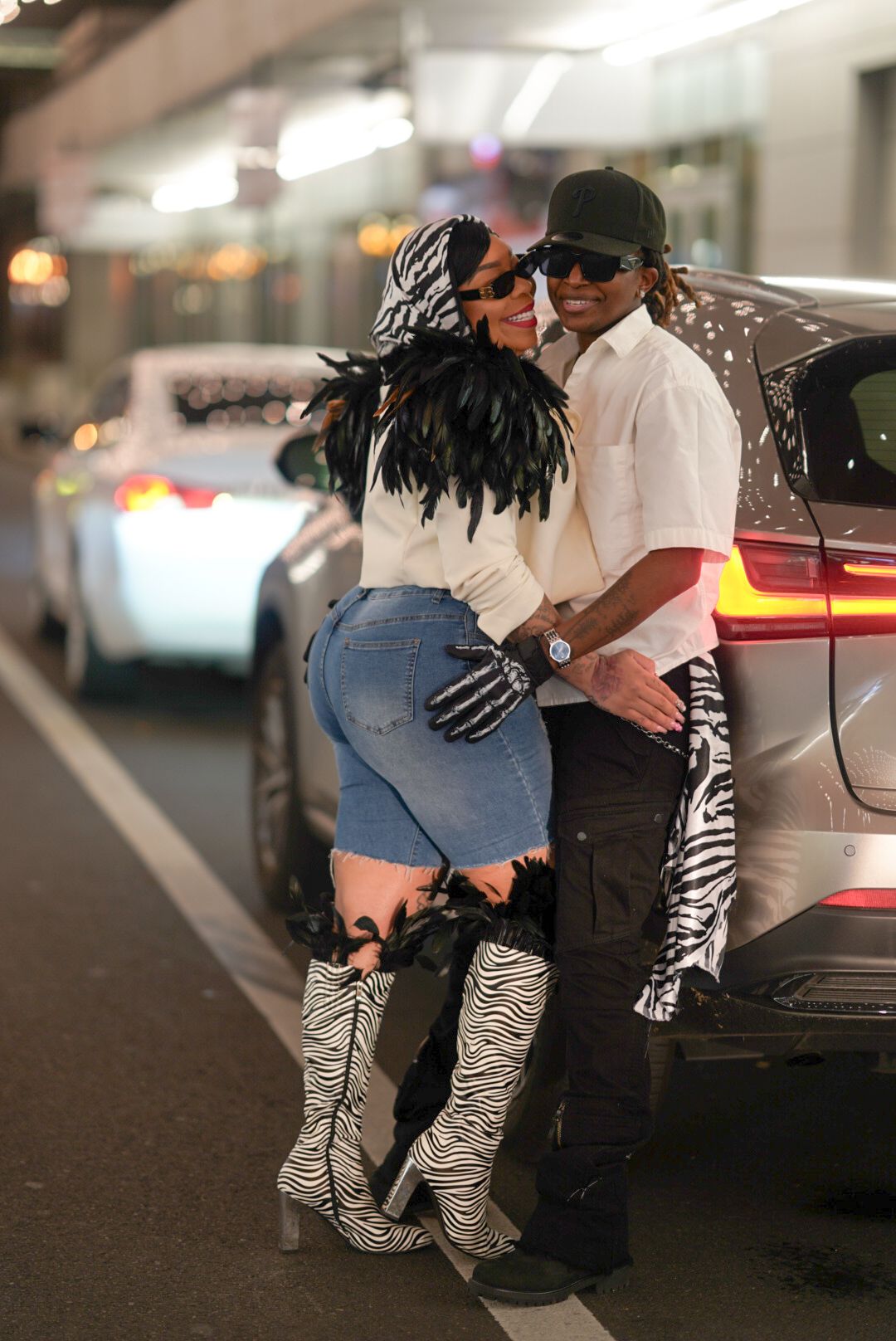 Stylish couple in urban setting wearing zebra print boots and casual attire.