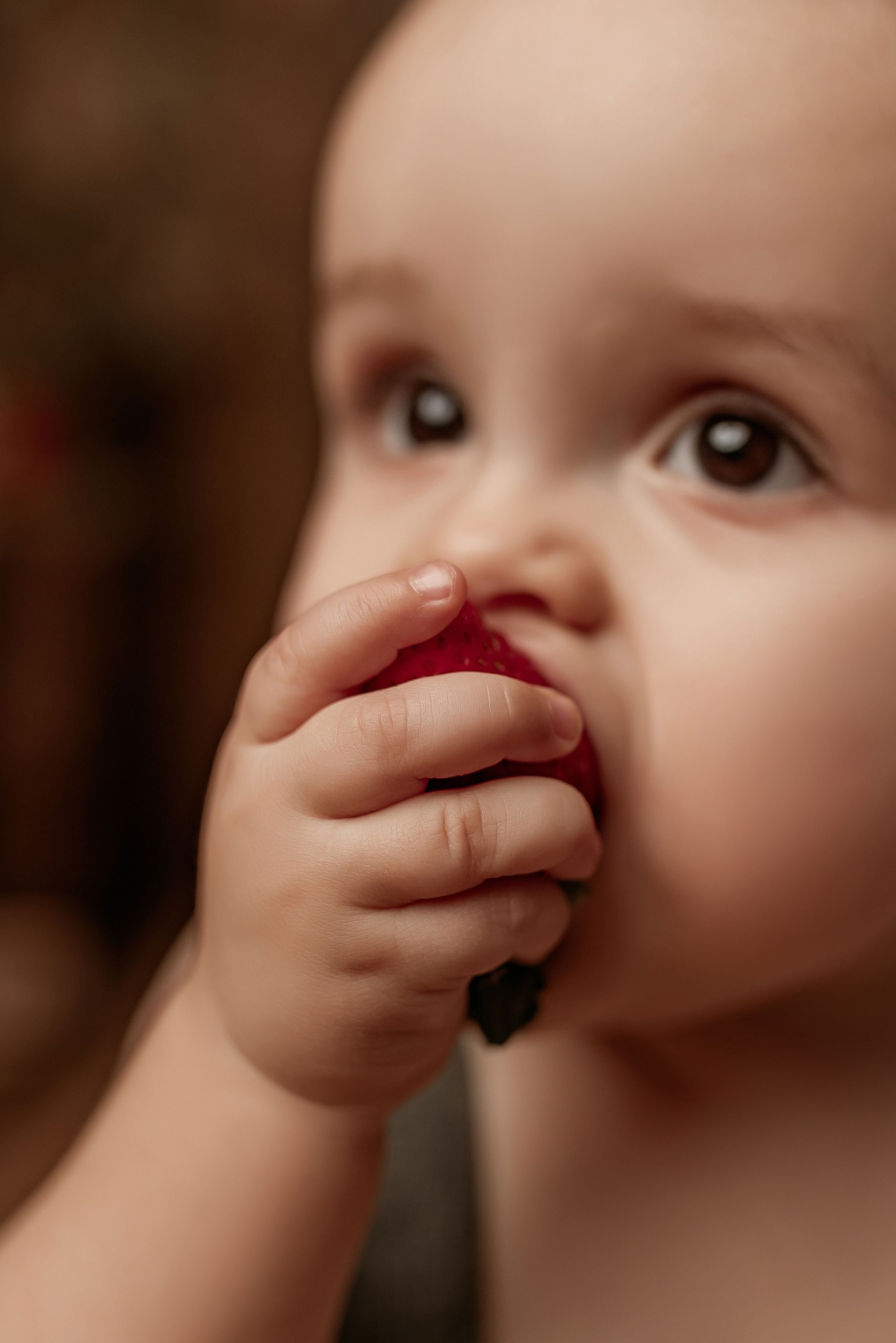 Close up photo of a young child's hand covering their mouth in a warm sepia tone.
