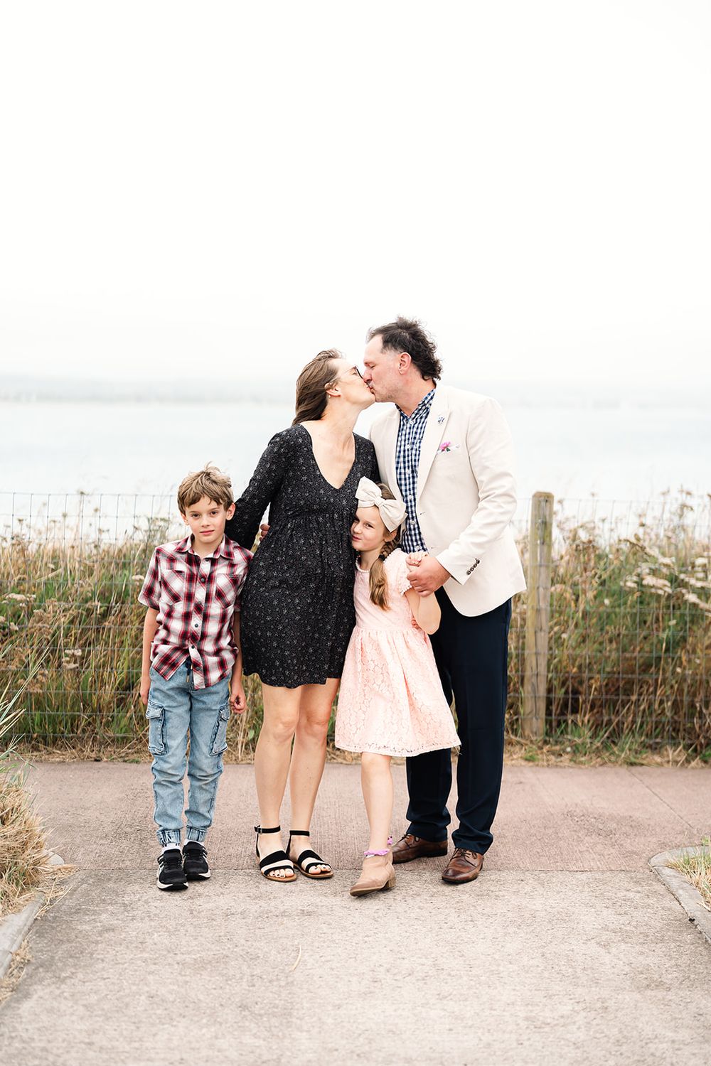 Family sharing tender moment together on coastal path with ocean view.