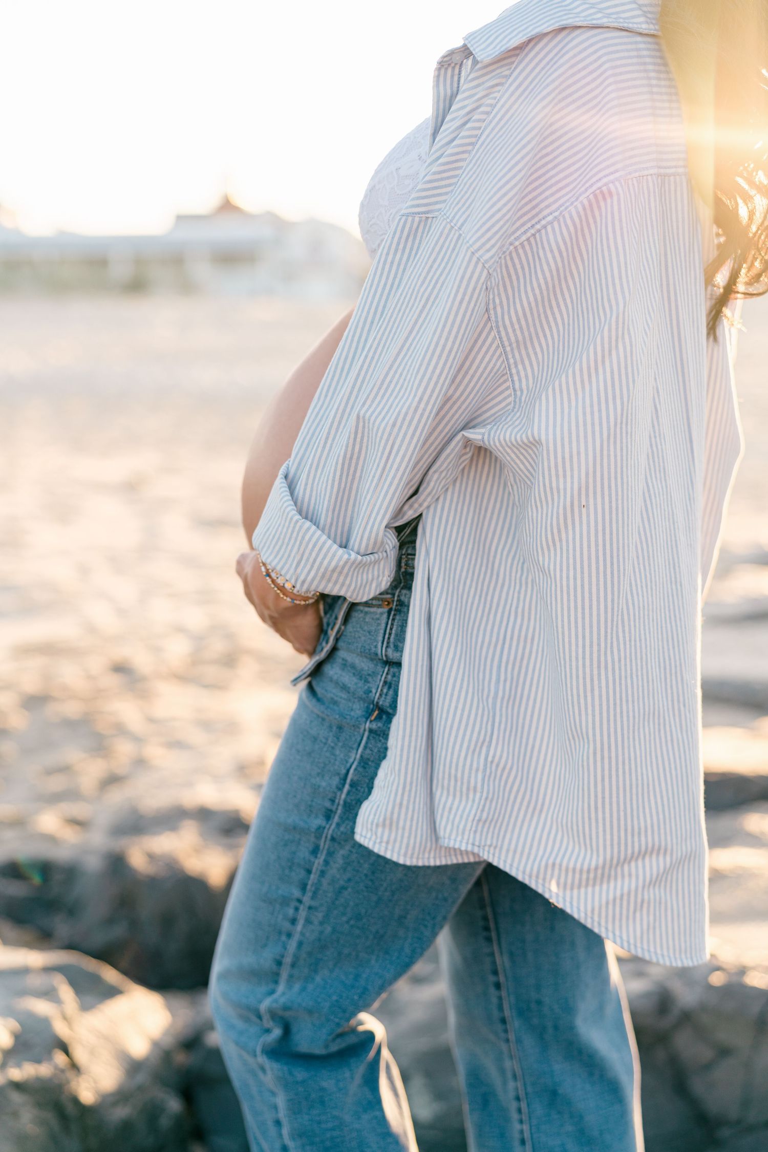 A close up of a maternity belly with the sunset on the beach in NJ.
