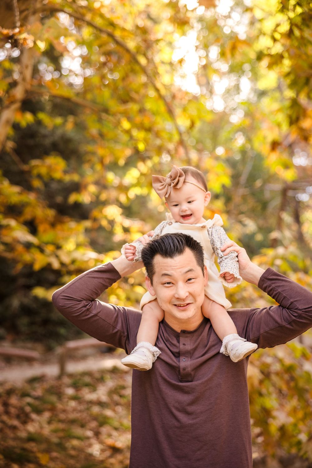 A tender autumn moment captured outdoors with warm lighting and golden foliage in the background.