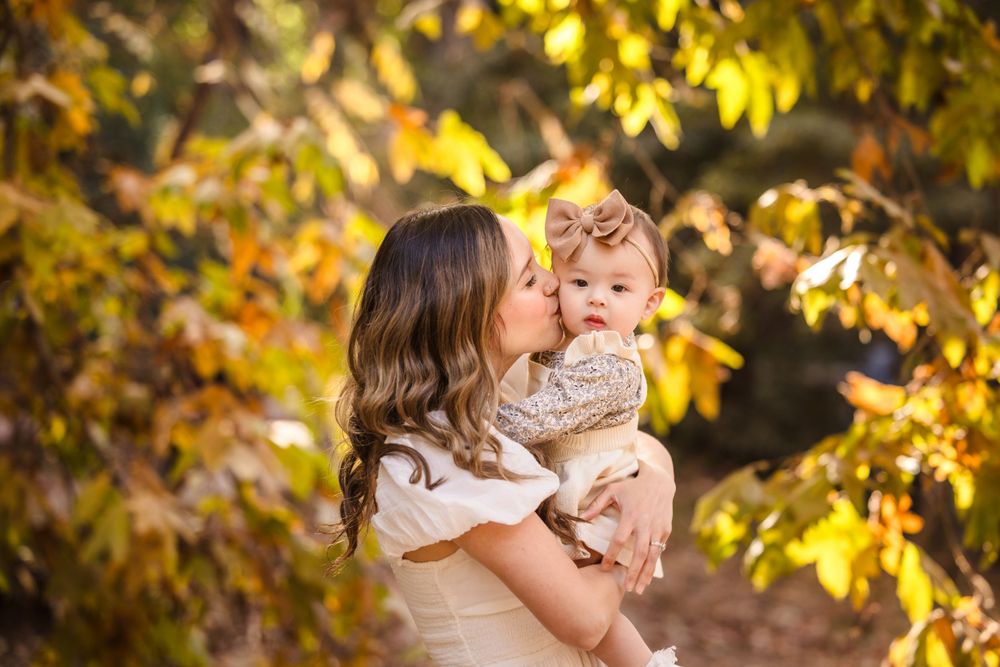 A tender autumn moment captured outdoors with golden foliage and warm lighting.