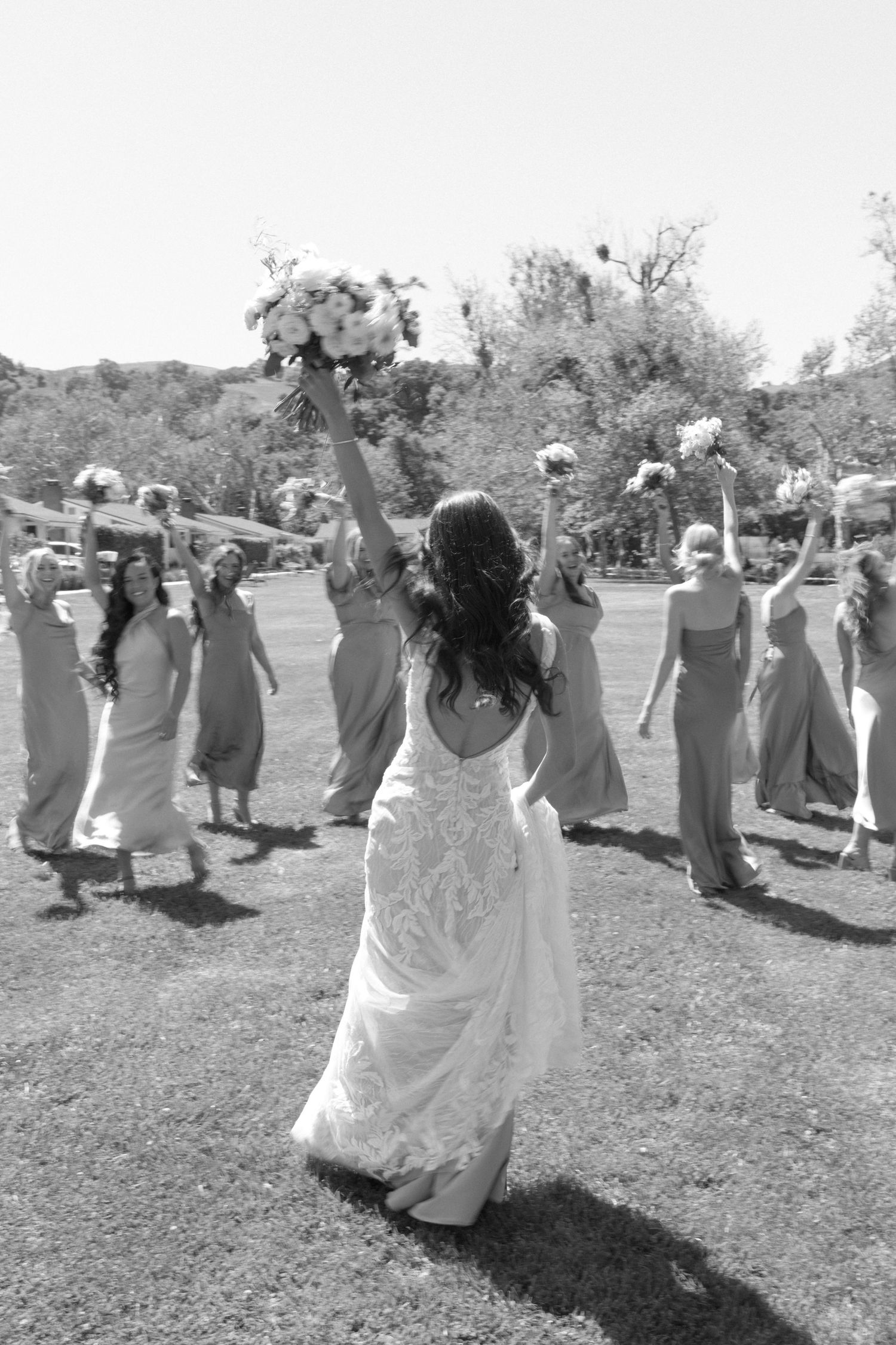 A celebratory moment with people raising bouquets in the air during a wedding celebration.