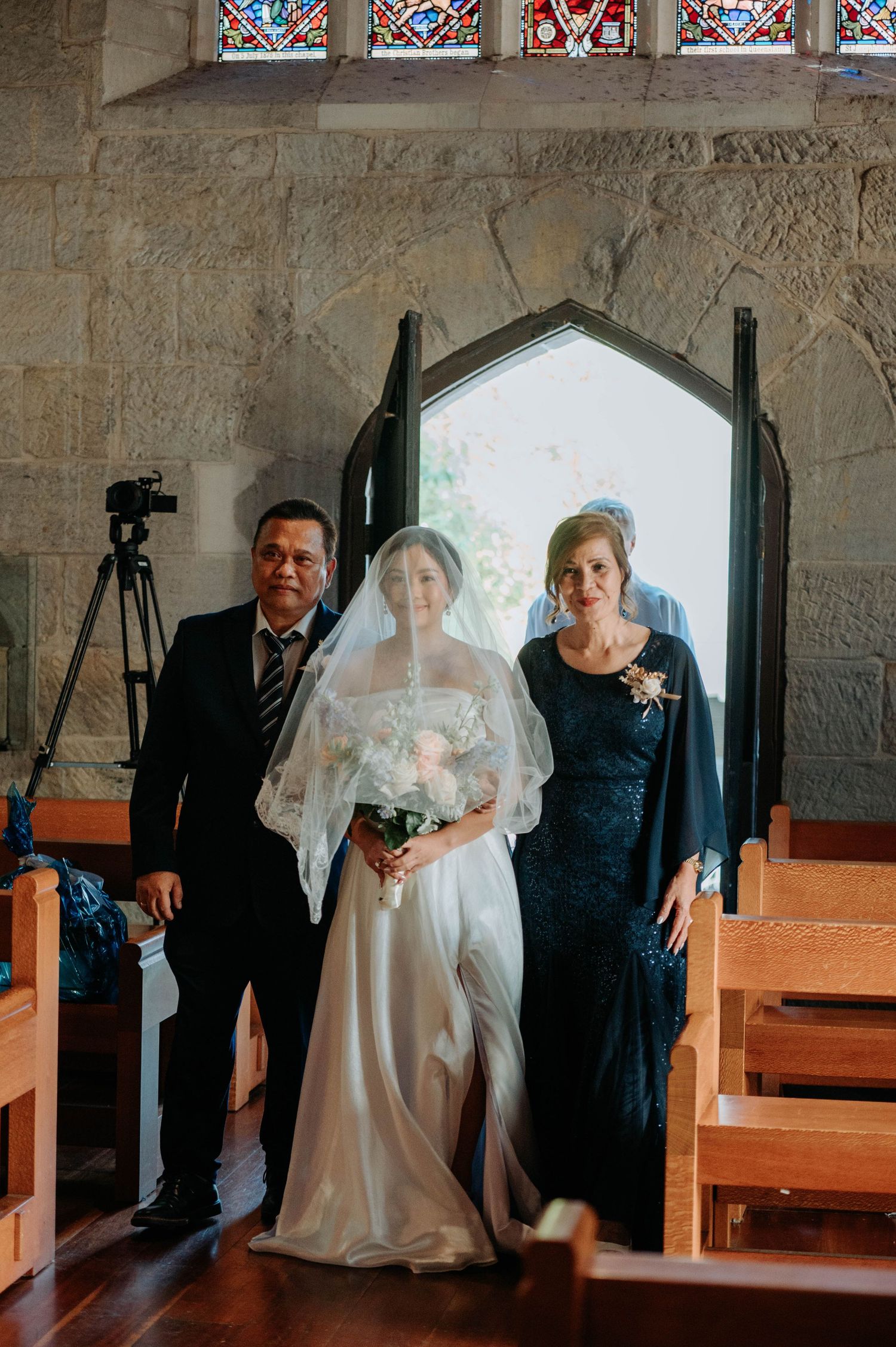 Traditional church wedding portrait with couple and family members under ornate window.