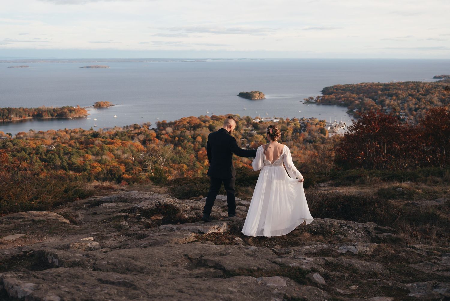 Panoramic wedding photography at sunset with couple on hilltop path.