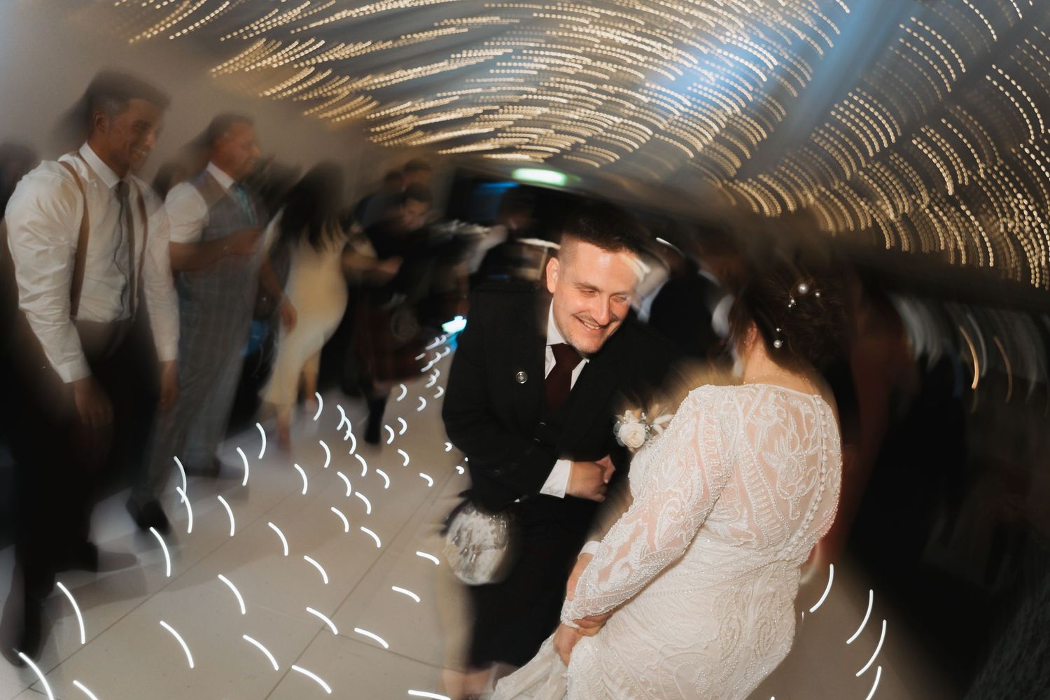 Blurred motion dance shot at a wedding reception showing people celebrating under twinkling lights.