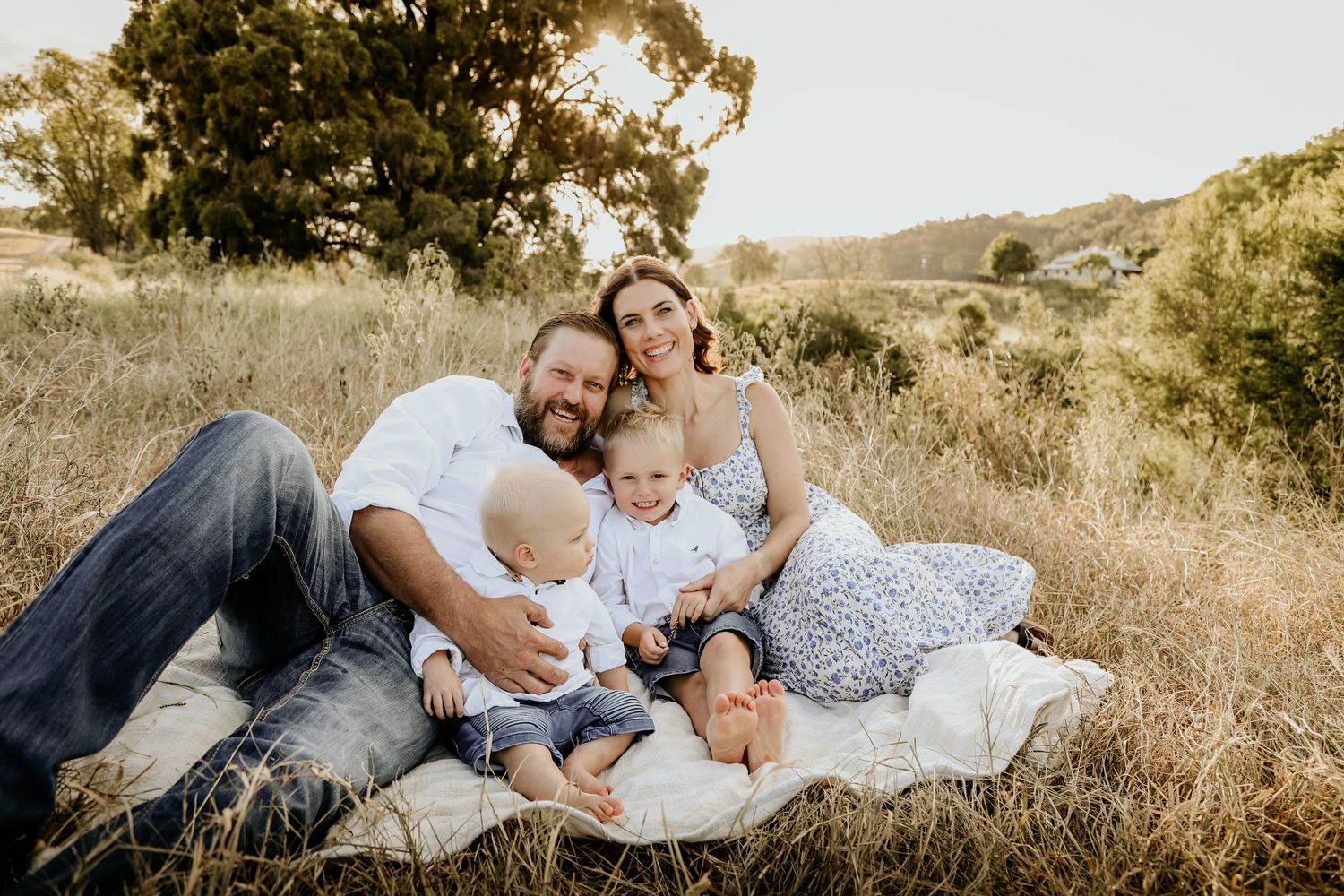 Family sitting in a paddock on sunset.
