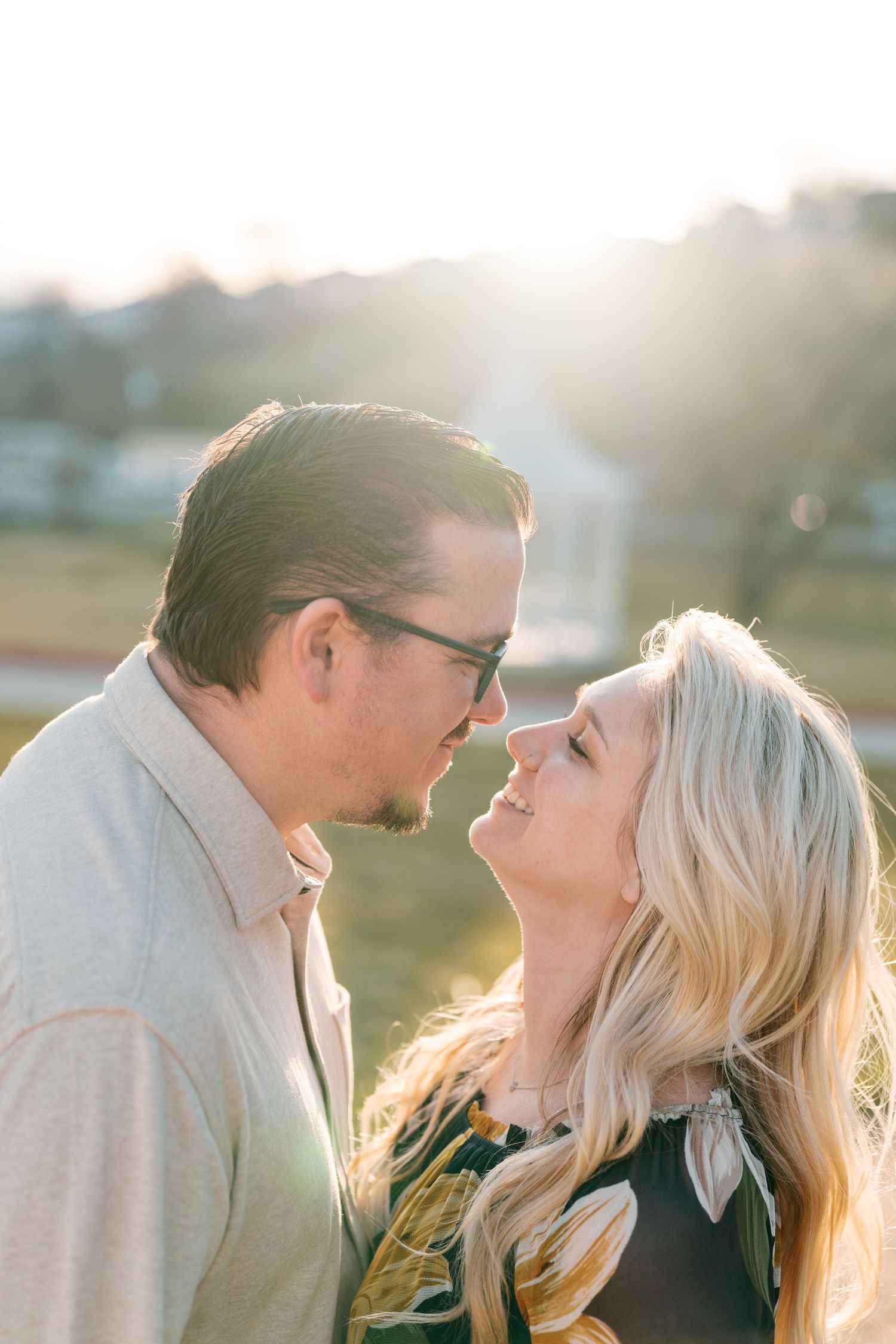 Romantic couple shares an intimate moment together at sunset with golden light glowing behind them.