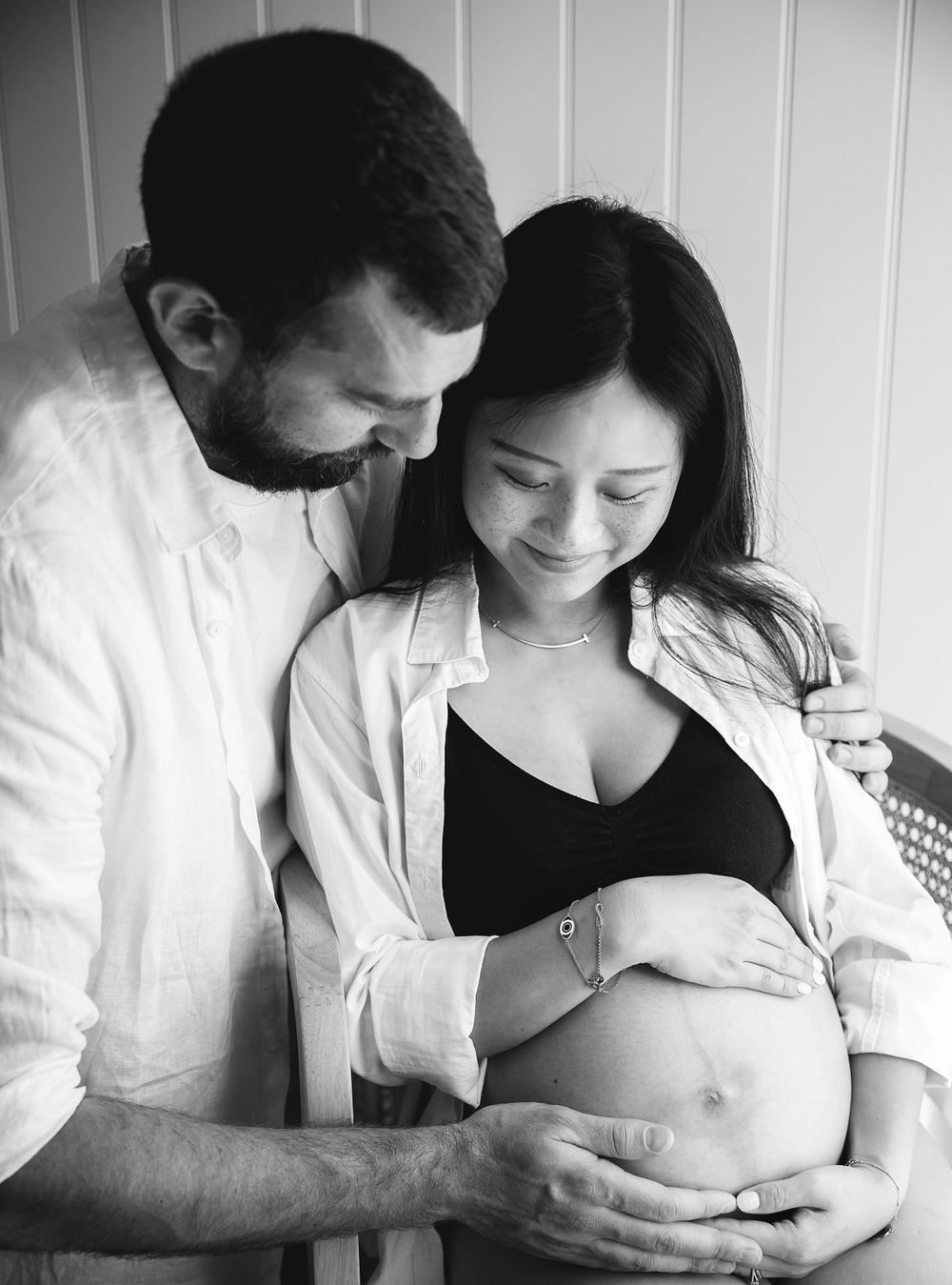 A loving couple shares an intimate black and white moment while expecting their first child.