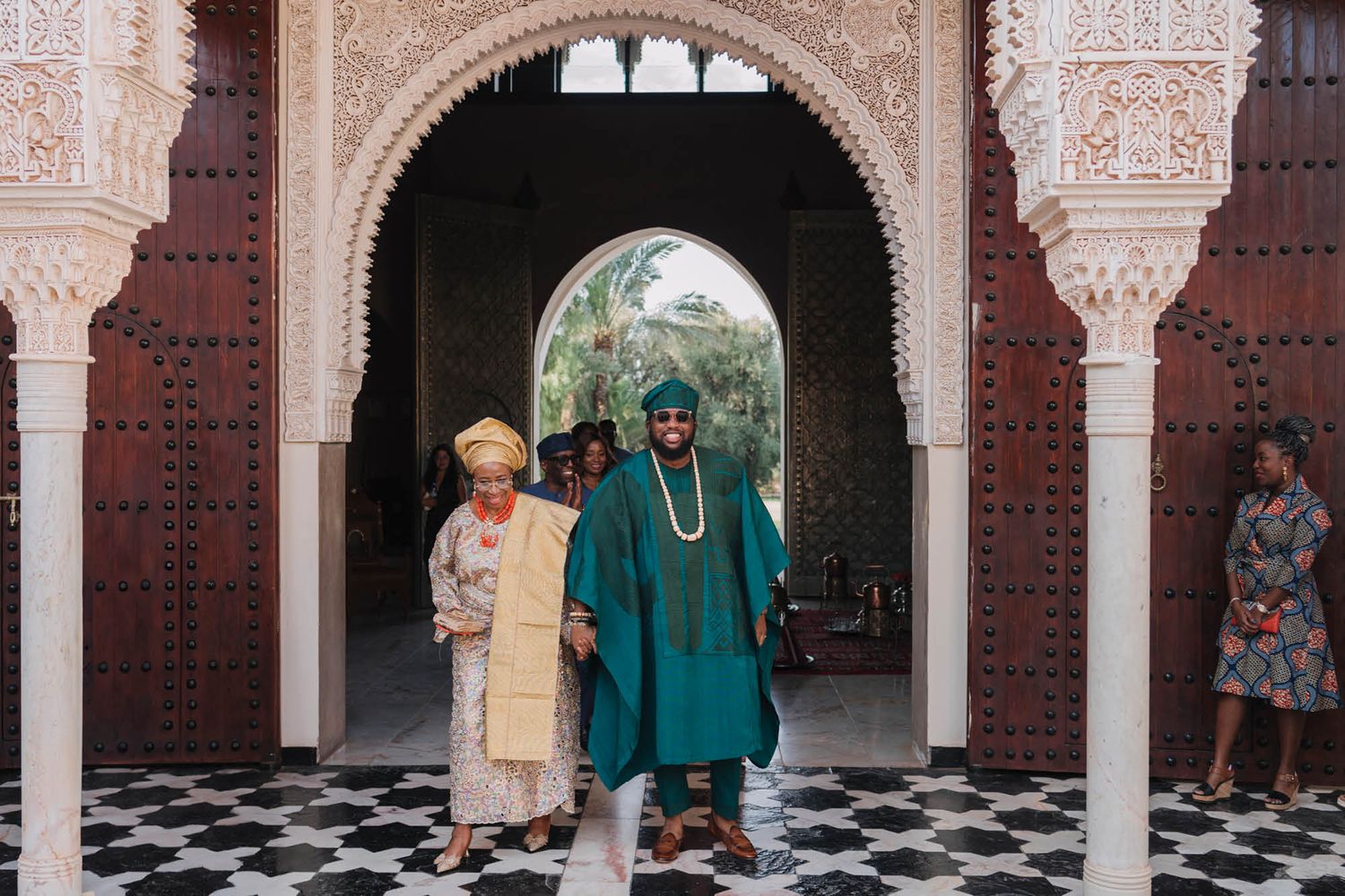 Traditional Moroccan archway with ornate carvings and a black and white checkered floor graces a cultural building.