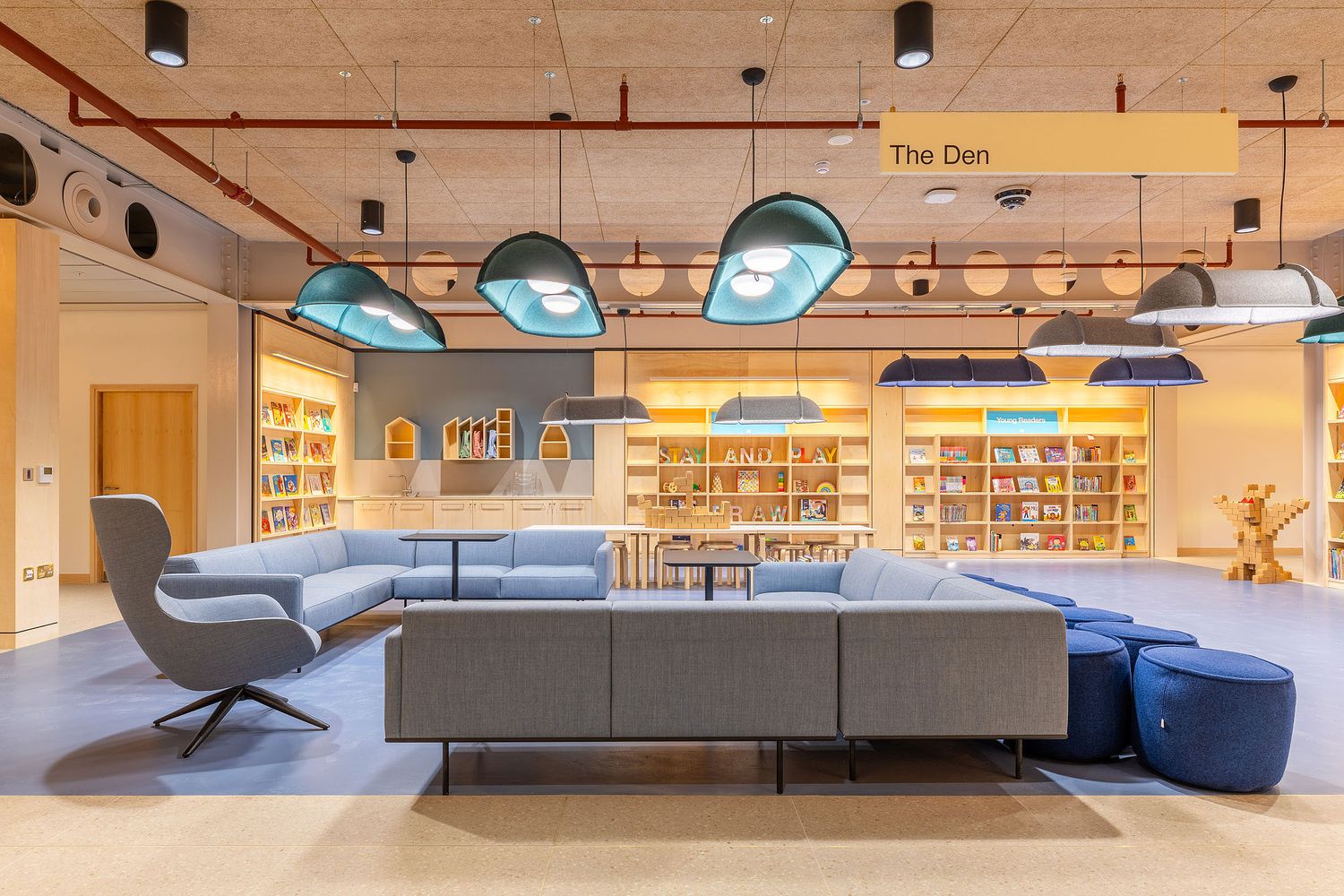 Contemporary library lounge with designer seating, feature lighting, children's reading area and open-plan collaborative spaces.