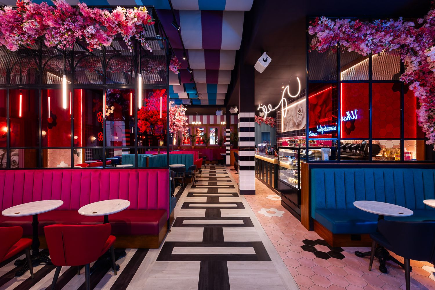 Vibrant café interior with bold colors, floral décor, neon lighting, and stylish booth seating for a modern, playful atmosphere.