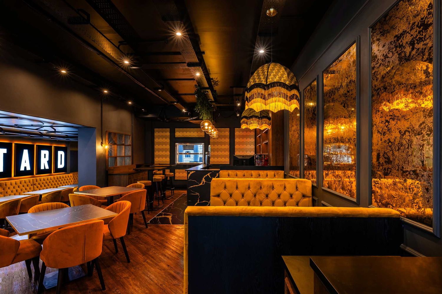 Moody restaurant interior with golden lighting, velvet banquette seating, marble tables, and textured walls creating a warm, elegant dining.