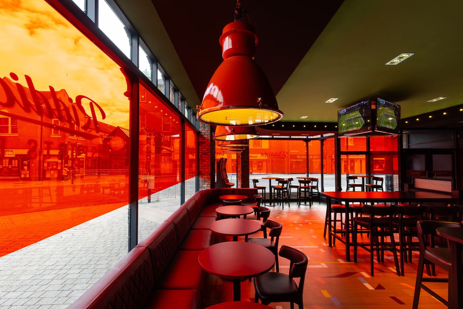 Vibrant bar interior with bold red lighting, tinted windows, and modern seating creating a striking contemporary atmosphere.