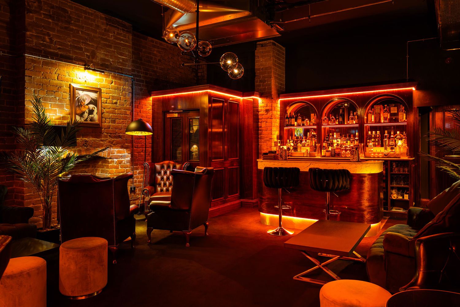 Cozy lounge with exposed brick, leather chairs, warm lighting, a fireplace, and industrial accents creating a sophisticated ambiance.
