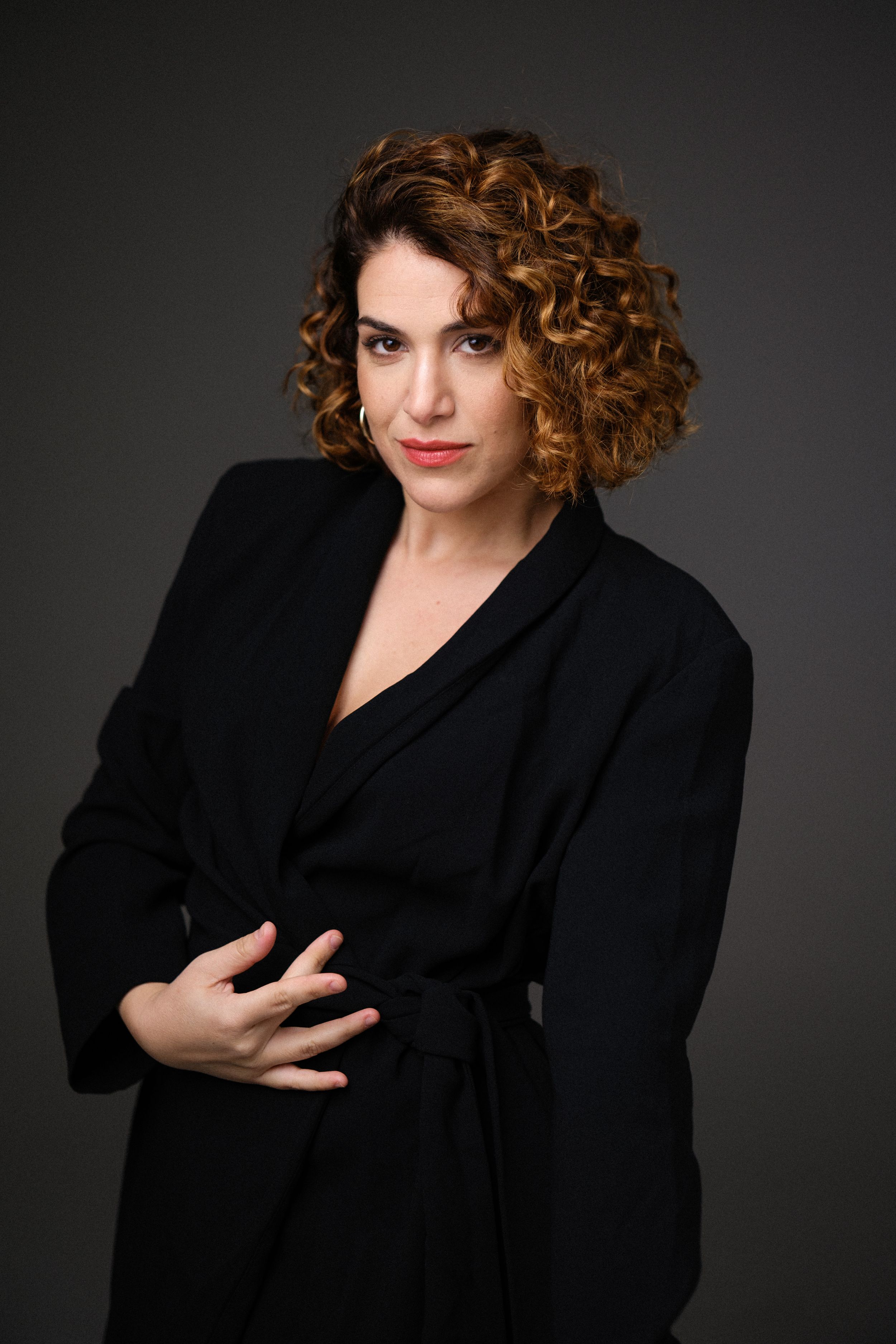 Artistic portrait in black blazer with dynamic hand gestures.