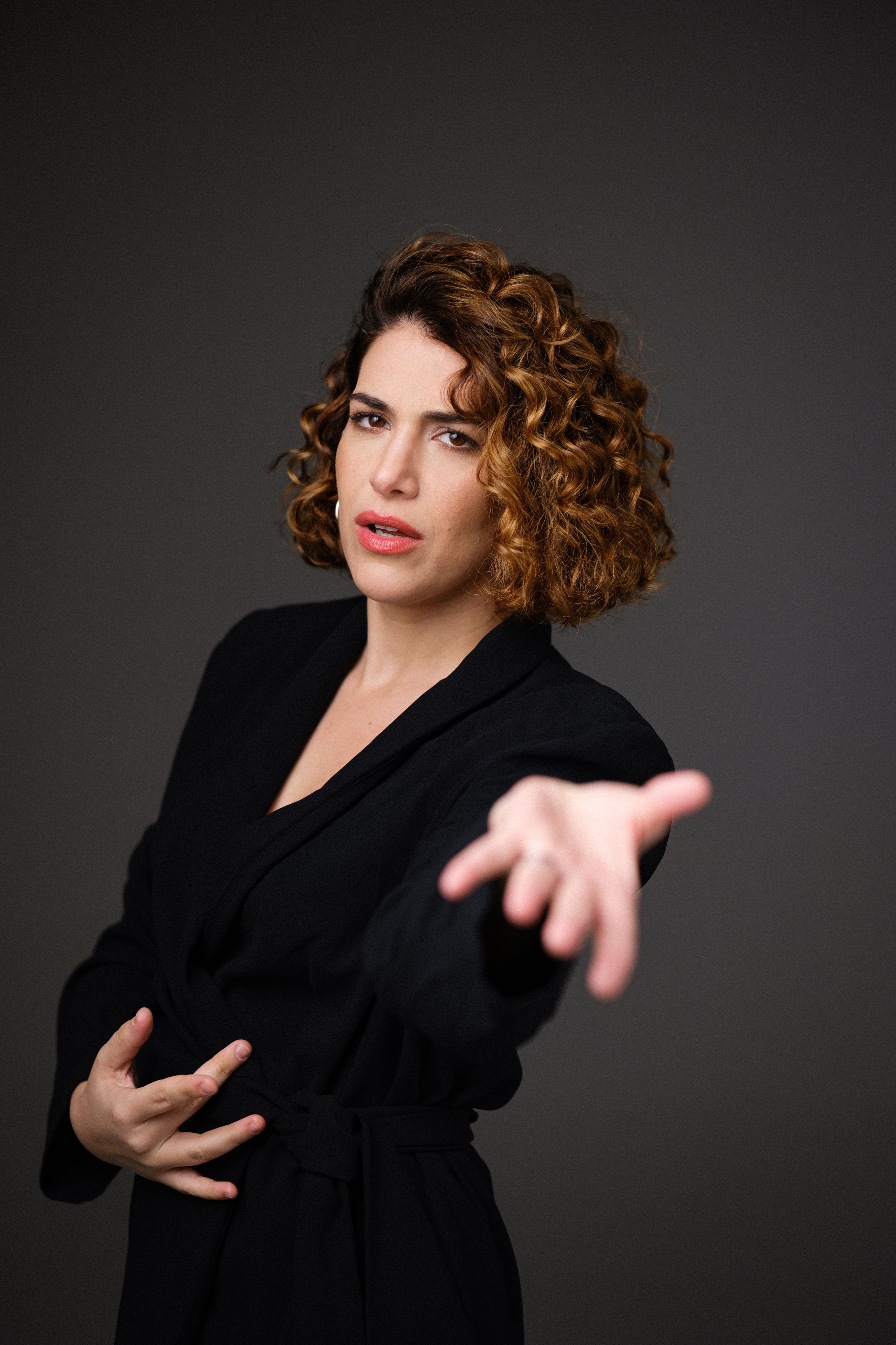 Expressive studio shot with animated hand gestures and black attire.