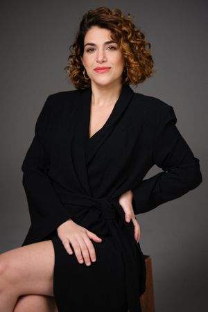 Elegant fashion portrait featuring black wrap dress and natural curls in studio setting.