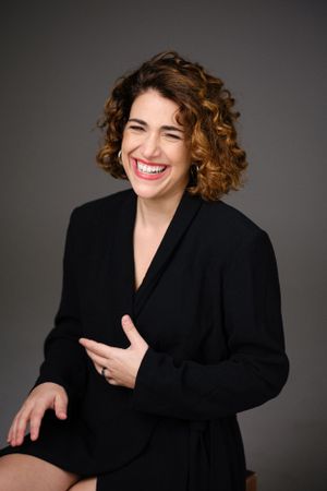 Expressive studio portrait with genuine laughter in classic black attire.