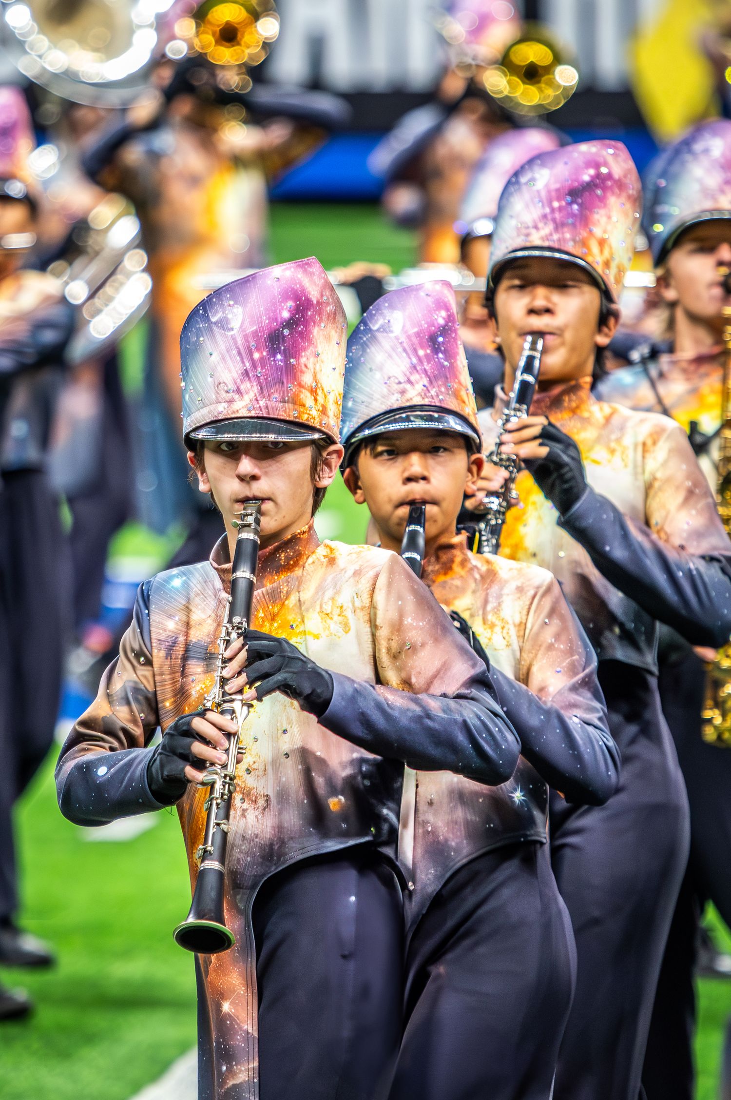 Marching band members in colorful uniforms play clarinets during field performance.